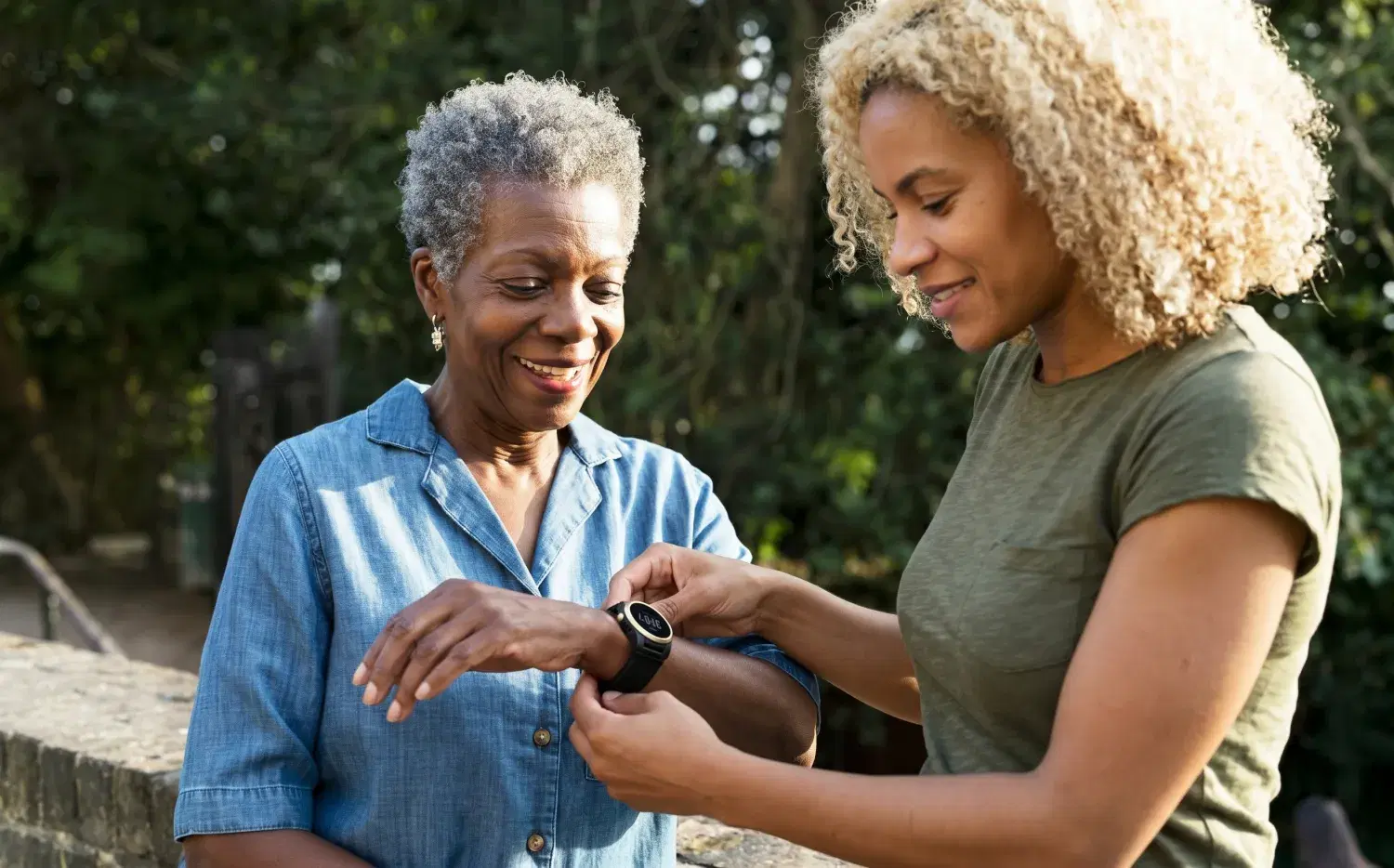 A woman helps an older woman set up her Kanega Watch outdoors