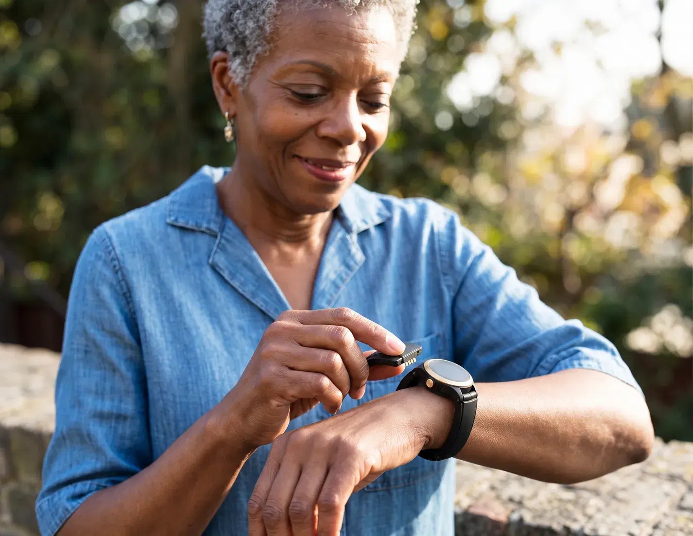 An older woman swaps the battery on the Kanega Watch on her wrist