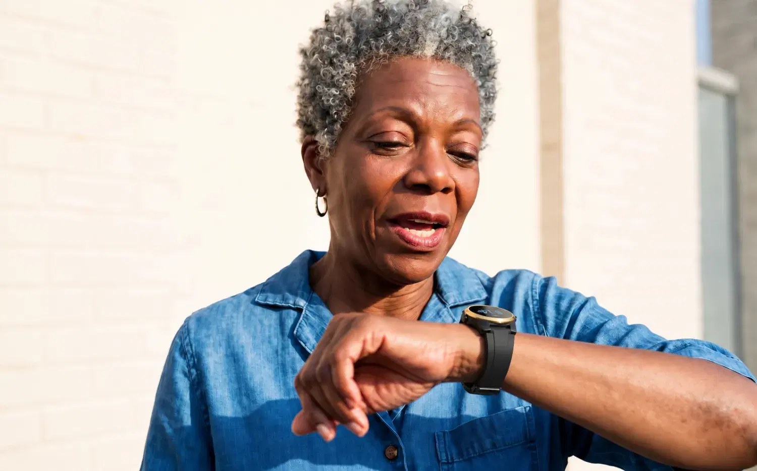 An older woman speaks into her Kanega Watch to get help